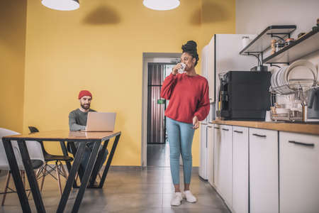 Friendly girl with coffee and guy working at laptopの写真素材
