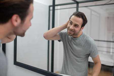 Man near the mirror scrutinizing himselfの写真素材