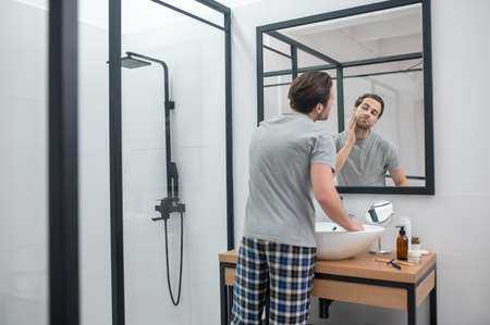 Man near the mirror scrutinizing himselfの写真素材