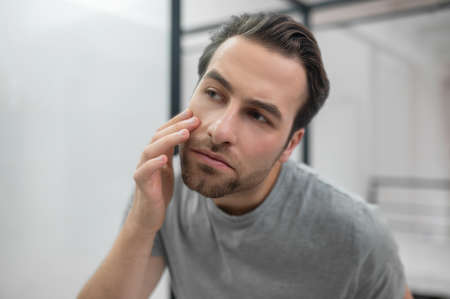 Man near the mirror scrutinizing himselfの写真素材