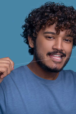 Serene Indian guy using the tooth floss