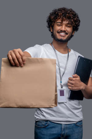 Male with a package and documents posing for the camera