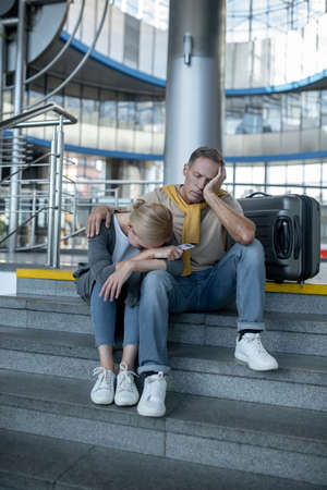 Exhausted tourist couple napping at the airport terminalの写真素材