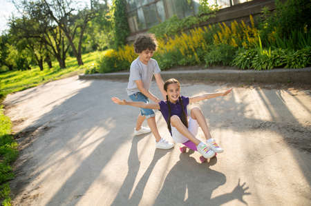 Boy teaching a girl how to skateboardの写真素材