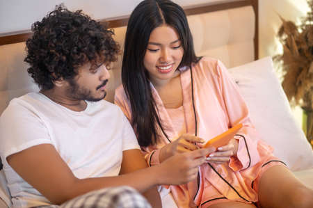 Man and woman interestedly looking at tablet on bed