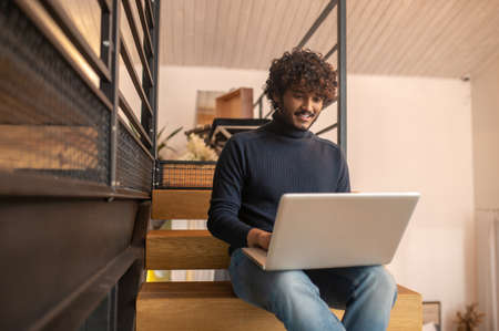 Man looking at laptop screen sitting on stairs