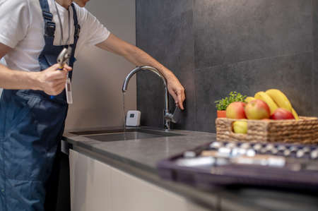 Plumber hand opening water tap in kitchen