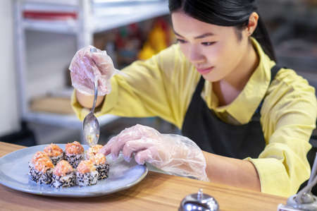 Asian woman putting sushi on the plate and looking inspiredの写真素材