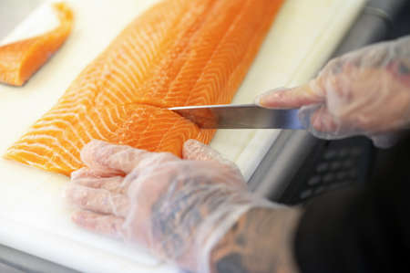 Close of mans hands cutting fish on a cutting boardの写真素材