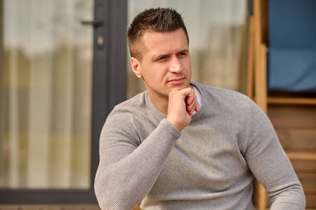 Man near house looking pensively to side