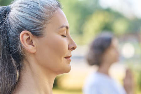 People in the park standing with hands in namaste and their eyes closedの写真素材