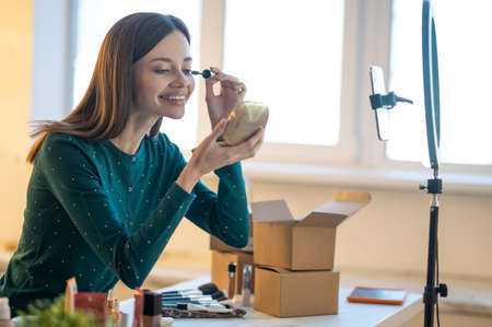 Young beautiful woman demonstrating new mascara and looking amusedの写真素材