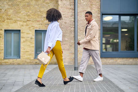 Man and woman walking towards each other on street