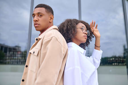 Man and woman standing back to back on street