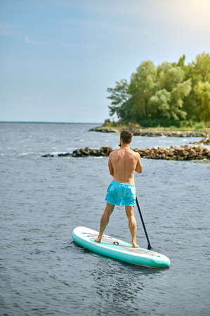 A man in blue swimming shorts with a kayak