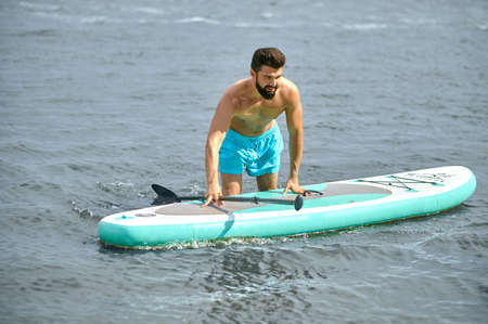 A man in blue swimming shorts with a kayak