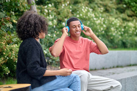 Man in headphones and woman sitting in park