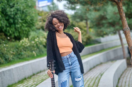Woman touching guitar looking at cameraの写真素材