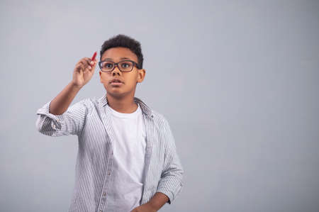 Serious concentrated kid drawing with a pencilの写真素材