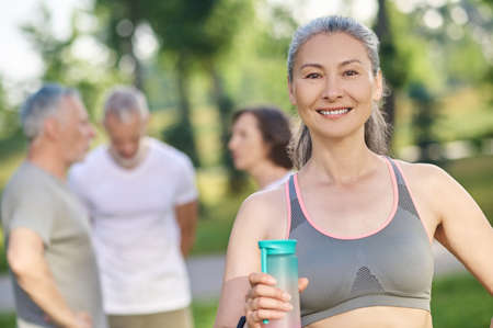 A sporty woman with a bottle of water in handsの写真素材