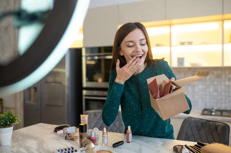 Young woman in green dress conducting online cosmetic saleの写真素材