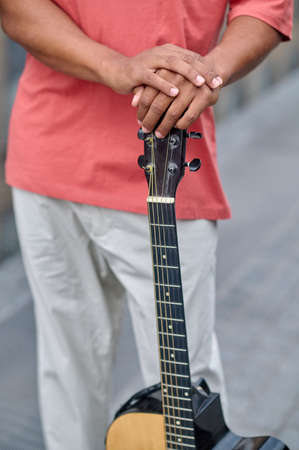 Hands of man standing in street touching guitar
