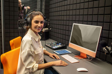Smiling female sound engineer seated at the desk looking aheadの写真素材