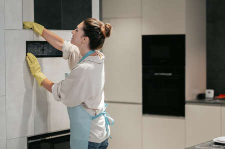 A woman in apron doing some housework and looking involvedの写真素材