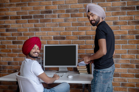 Two indian men working together and looking contentedの写真素材