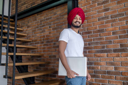 Young indian man in red turban standing on stairsの写真素材