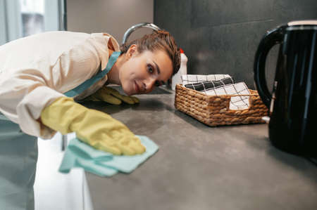 Young dark-haired woman cleaning the surfaces in the kitchenの写真素材
