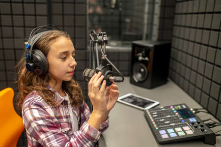 Teenage girl checking her mike before recording a podcastの写真素材