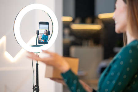 Young smiling beauty coach presenting new beauty products to online audience