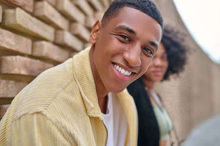 Close-up man smiling at camera and woman outdoorsの写真素材