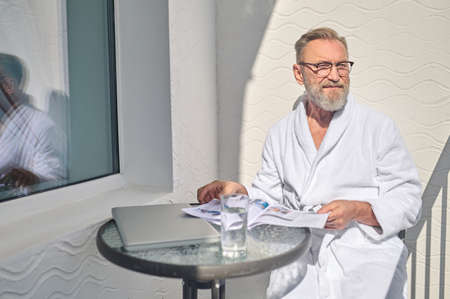 Tranquil holidaymaker seated on the balcony staring into the distanceの写真素材