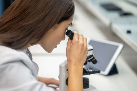 Close-up of womans face looking through microscopeの写真素材