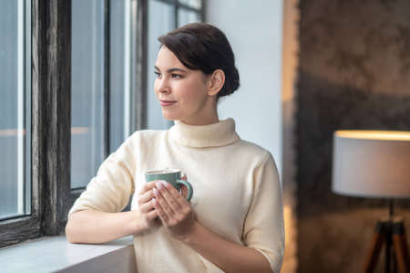Serene thoughtful female staring out of the window