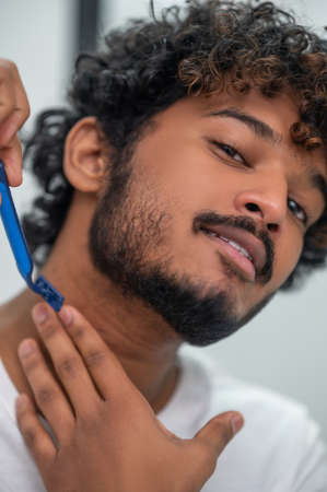 Focused male using a safety razor for neck hair removalの写真素材