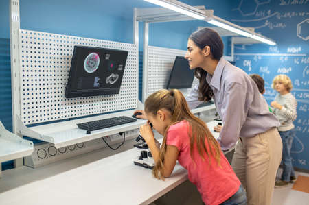 Woman looking at charging board and girl near microscopeの写真素材