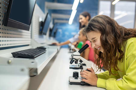 Girl sideways to camera looking into microscope with interestの写真素材