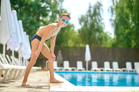 Boy standing at start near pool looking at cameraの写真素材