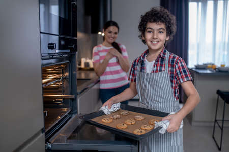 Boy with cookie sheet looking at camera