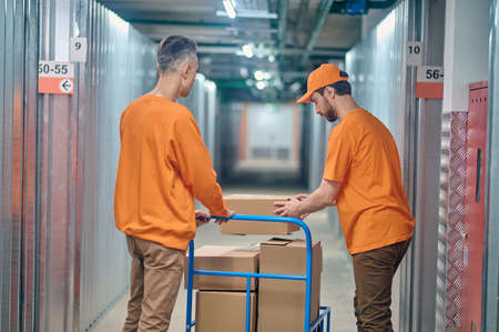 Loaders stacking boxed goods on the warehouse trolleyの写真素材