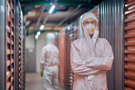 Two warehouse employees wearing protective gear in the storage areaの写真素材