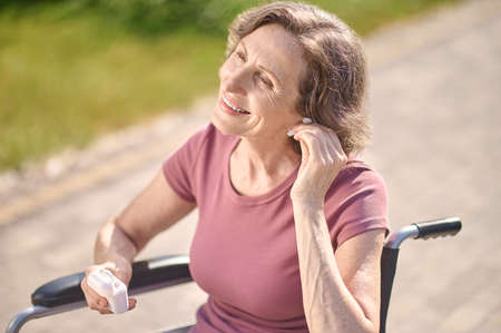 A smiling woman on a wheel-chair putting on wireless headphonesの写真素材