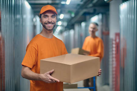 Male worker and his coworker unloading merchandise