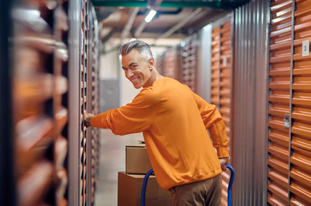 Happy storehouse worker standing among cargo containersの写真素材