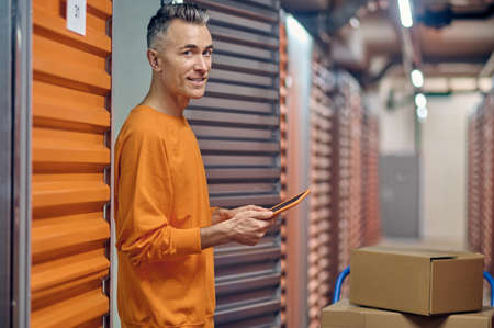 Joyous middle-aged warehouse employee among cargo containersの写真素材