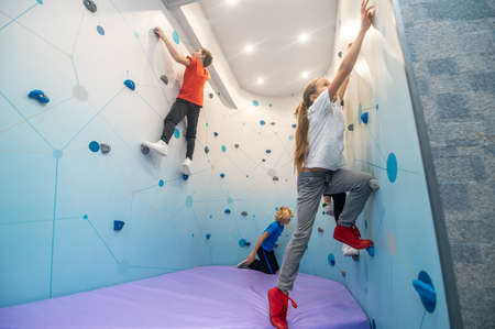 Children sideways to camera climbing wallの写真素材
