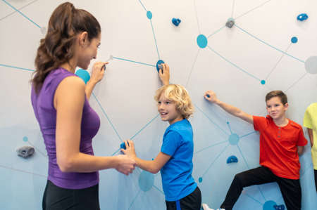 Boys near climbing wall looking at woman
